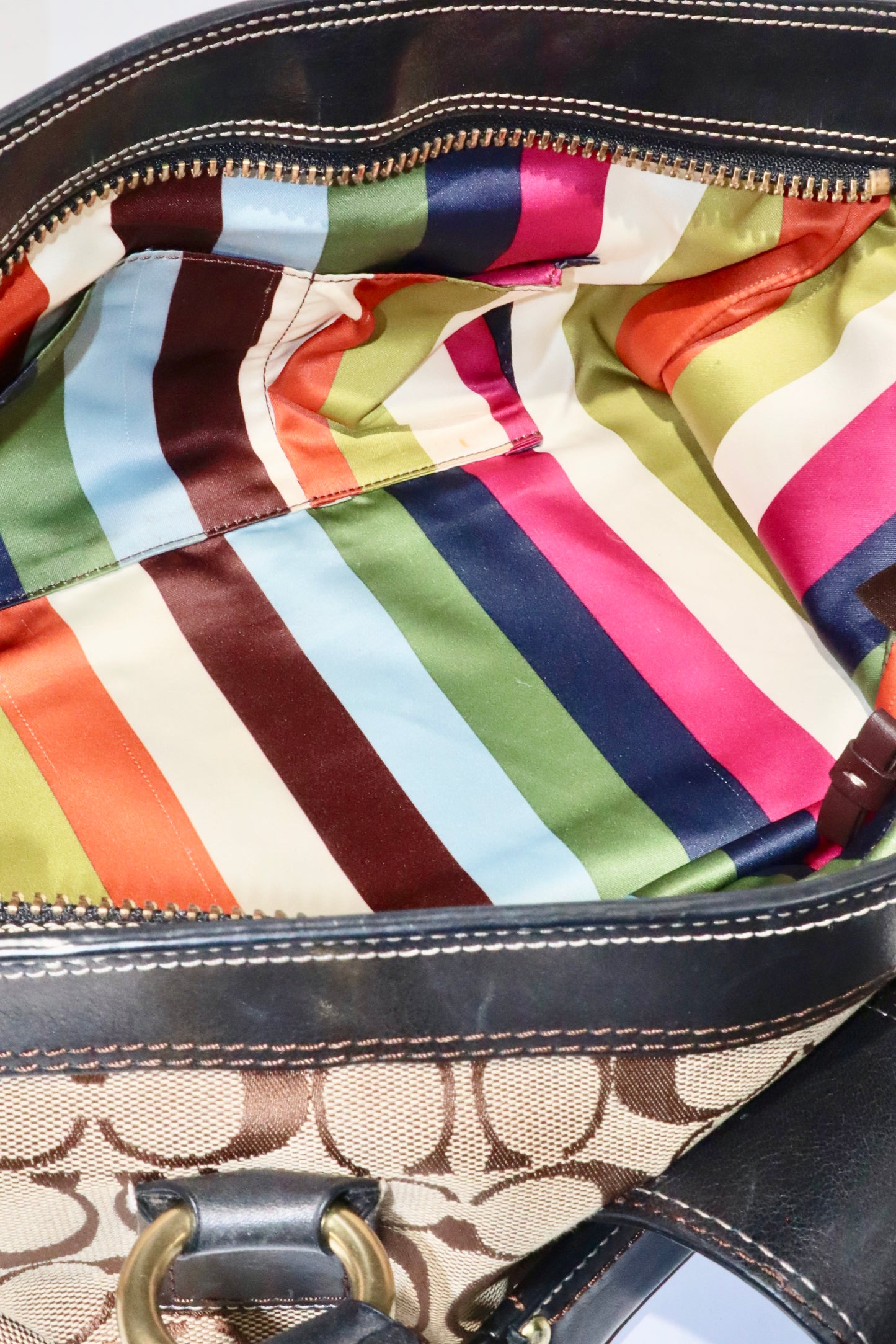 Interior view of Coach Brown Signature 65th Anniversary Legacy Turnlock Rare Edition with colorful striped satin lining.