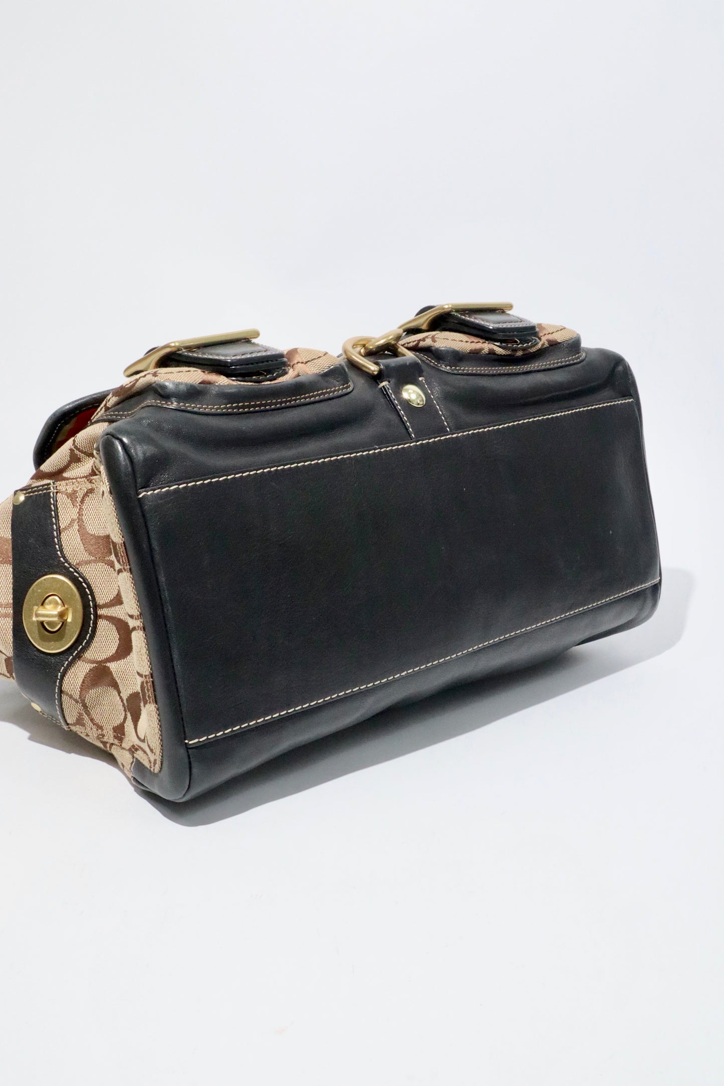 Coach Brown Signature 65th Anniversary Legacy Turnlock Rare Edition handbag side view showcasing canvas and leather material.