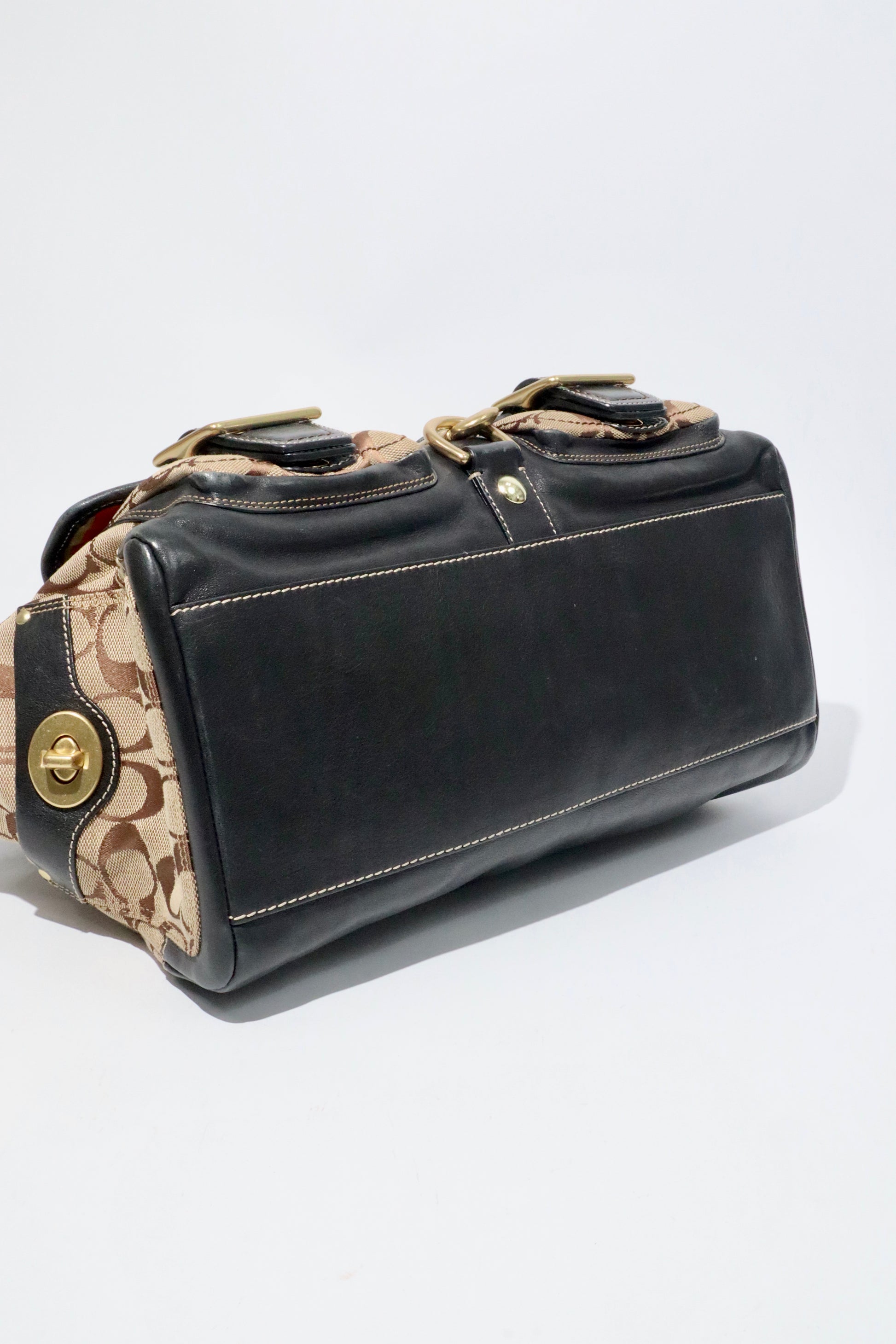 Coach Brown Signature 65th Anniversary Legacy Turnlock Rare Edition handbag side view showcasing canvas and leather material.