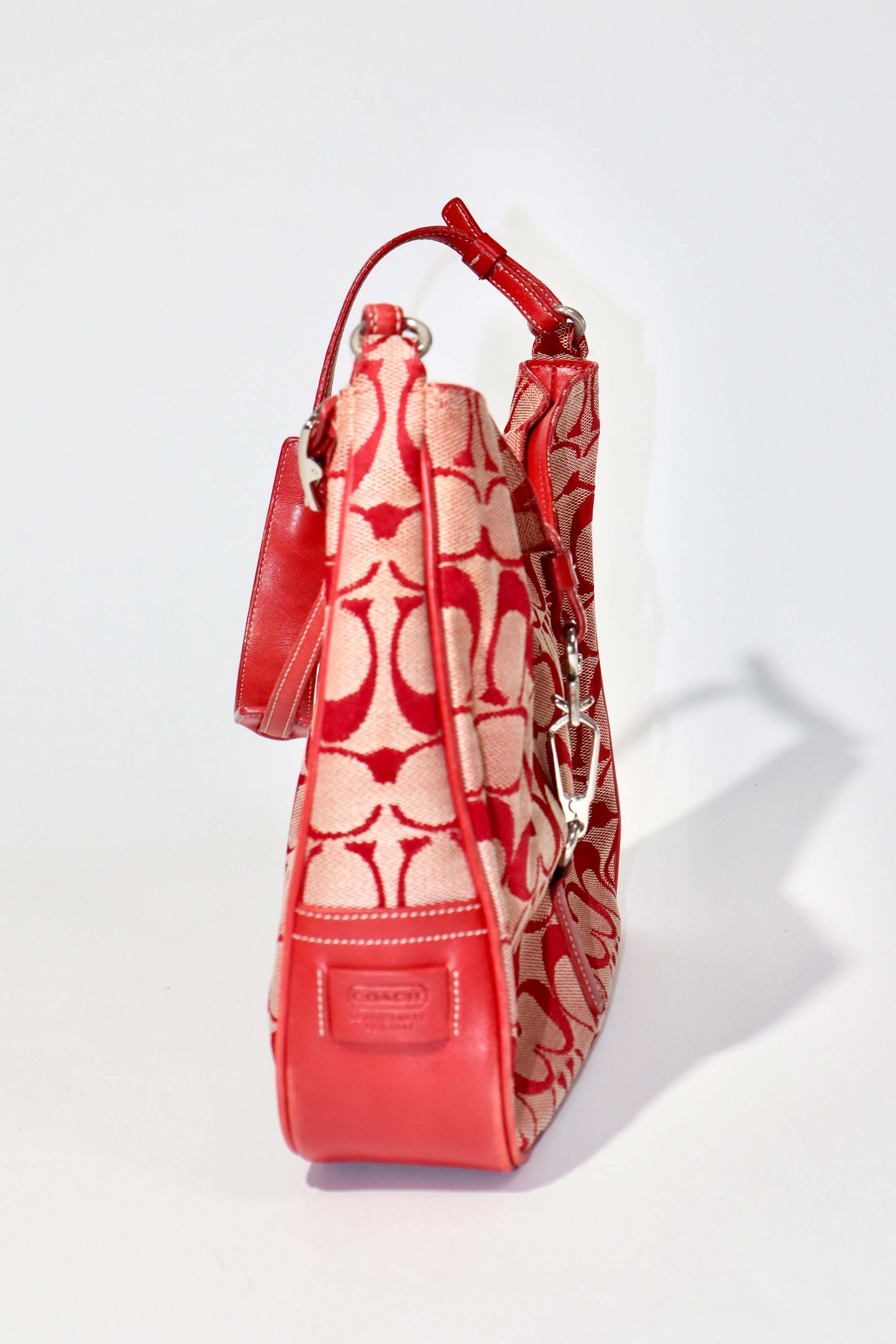 Vintage Coach 2001 Red Clip Tote Shoulder Bag shown from the side, featuring signature monogram canvas and bold red leather trim.